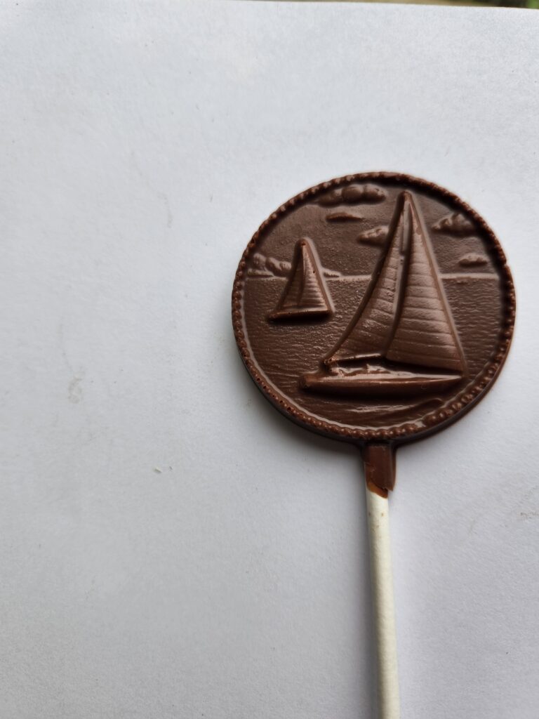 A solid chocolate sucker with a boat on it